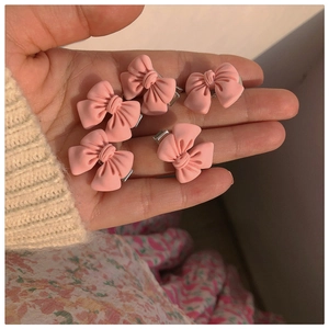 Set of five pink matte resin bow hair clips held in hand for size perspective