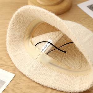 Close-up of beige plush knit bucket hat interior with sweatband and adjustable string