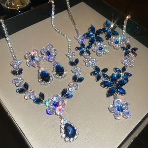 Macro shot of silver flower necklace and earrings set with blue crystals and starburst shine