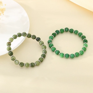 Green stone tiger eye beaded bracelets with silver spacers on a warm textured background