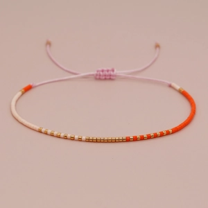 Bohemian handmade beaded bracelet with white, gold, and orange beads on pink cord