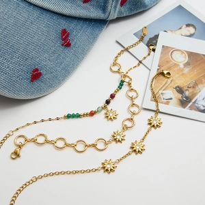 Detailed view of three gold stainless steel star bracelets with colorful beads and charms