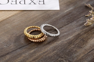 Detailed view of tricolor spiral wave rings in gold, silver, and rose gold on wood