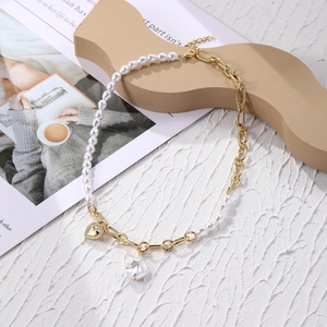 Detail of layered gold chain necklace featuring baroque pearl and sparkling heart pendant
