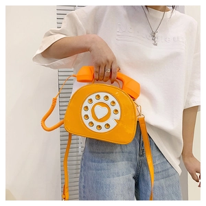 Detailed close-up of a vintage orange telephone-shaped patent leather crossbody bag