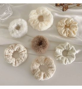 Flat lay of assorted plush and velvet hair scrunchies in cream and brown autumn shades