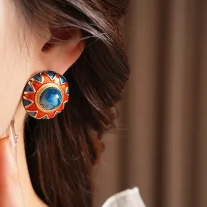 Vintage round enamel stud earrings with sunburst pattern and blue stone on model