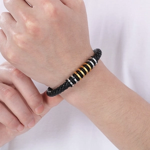 Close-up of woven black leather bracelet with mixed gold and silver stainless steel rings