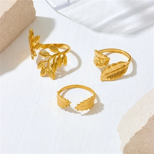 Minimalist gold leaf and feather adjustable stainless steel rings on a white stone background