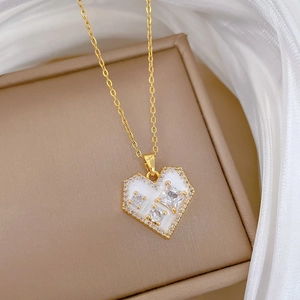 Macro view of gold heart necklace featuring white enamel and sparkling zircon inlay