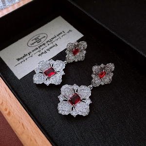 Macro shot of vintage silver flower earrings with red zircon in a black jewelry box