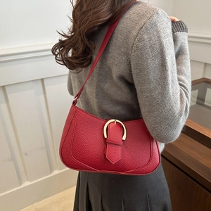 Red lychee pattern shoulder bag with gold horseshoe buckle worn with grey sweater