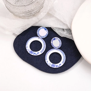 Detailed view of round blue and white porcelain earrings on a stylized display