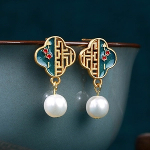 Macro shot of Chinese style enamel butterfly earrings with white pearls on a green ceramic bowl