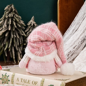 Pink sequined knit hat Christmas gnome plush doll sitting on a vintage book