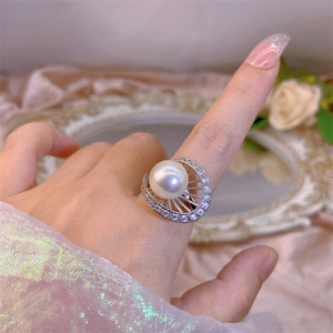 Close-up of a large white pearl ring with zircon-encrusted base on a woman's finger