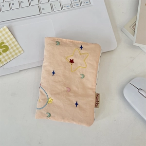 Close-up of peach quilted fabric passport holder with colorful star and moon embroidery