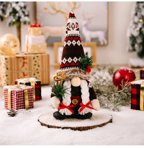 Close-up of Christmas gnome with knitted hat holding wooden skis on a snow surface