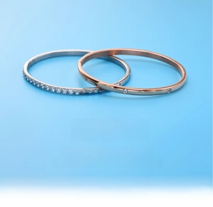 Close-up of silver and rose gold titanium steel bangles with sparkling zircon inlay