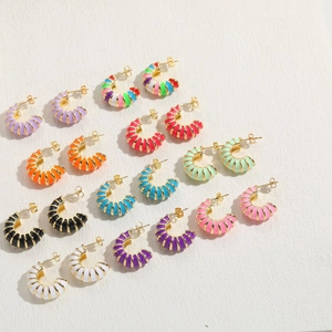 Macro detail of various colorful croissant enamel C-shaped hoop earrings with gold-plated edges