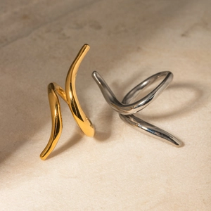 Artistic display of 18k gold and silver sculptural intertwined open rings on beige surface