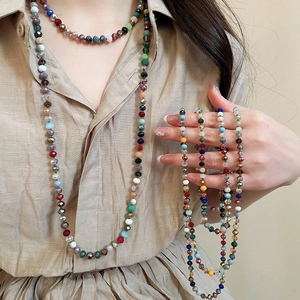 Detail of colorful faceted crystal beads and layered bohemian style necklace on a shirt