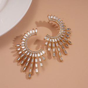Macro detail of gold C-shaped flower earrings with rectangle crystals and sparkling zircons