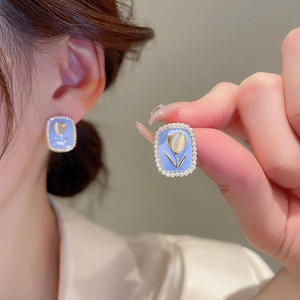 Close-up of vintage rectangle earrings with blue tulip design and tiny pearls