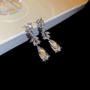 Macro shot of silver drop earrings featuring clear zircon crystals and tassels on velvet