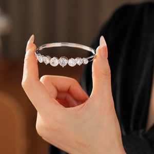 Detailed close-up of a silver bangle featuring seven round zircons on a wavy metal band