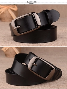 Detail view of black genuine leather belt with dark metal buckle on rustic background