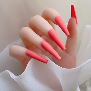 Vue macro de faux ongles ballerine extra longs rose corail mat avec un décor en tulle doux