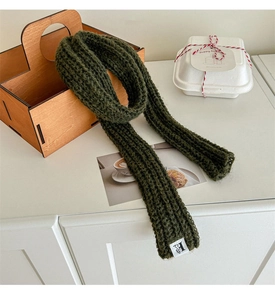 Close-up of deep green chunky knit wool scarf with a white H-label and soft texture