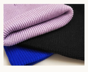 Detail shot of knitted beanies in lilac, black, and royal blue with thick wool texture