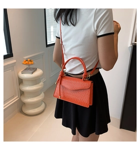 Detail of orange epi-leather crossbody bag featuring stylish artistic knotted handle design