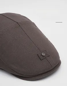 Dettaglio cappello newsboy in lino marrone scuro con tesa larga e fibbia in metallo retrò