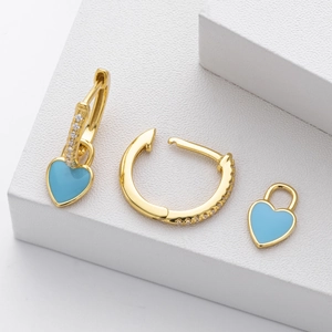 Macro shot of light blue enamel heart charm and micro-inlaid zircons on gold earrings