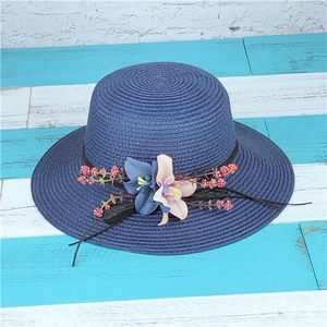 Dettaglio cappello in paglia blu scuro con fiori in seta fatti a mano e bacche rosse