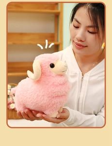 Close-up of a soft pink plush sheep toy with white curly horns held in hands