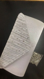Detail of silver rhinestone evening bag with pleated satin finish and metal chain strap