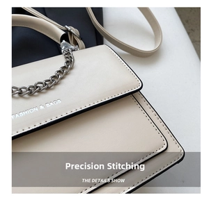 Close-up of precise stitching on off-white leather bag with silver hardware detail