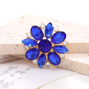 Close-up of blue gemstone flower accessory with clear crystal accents on gold plating