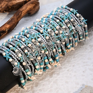 Detail of layered turquoise beaded anklet set with ocean pendants on black display