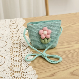 Detail of mint green straw woven crossbody bag with pink fabric flower and zipper closure