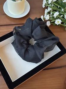 Dettaglio della trama di uno scrunchie in rete nera traslucida su vassoio decorativo