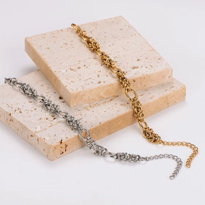 Elegant gold and silver link chain bracelet displayed on beige travertine stone blocks