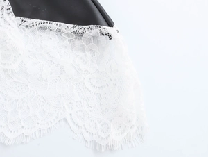 Détail d'une robe en cuir PU noir avec empiècement en dentelle blanche et bordure cil