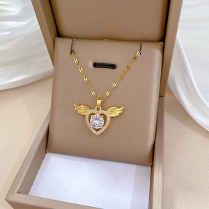 Close-up of golden heart necklace with wing design and zircon inlay in a gift box