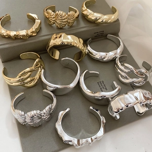 Detailed collection of gold and silver irregular textured metal open bangles on books