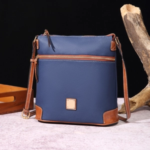 Detail of navy blue pebble leather crossbody bag with brown trim on wooden background